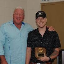 Two men, one holding an award